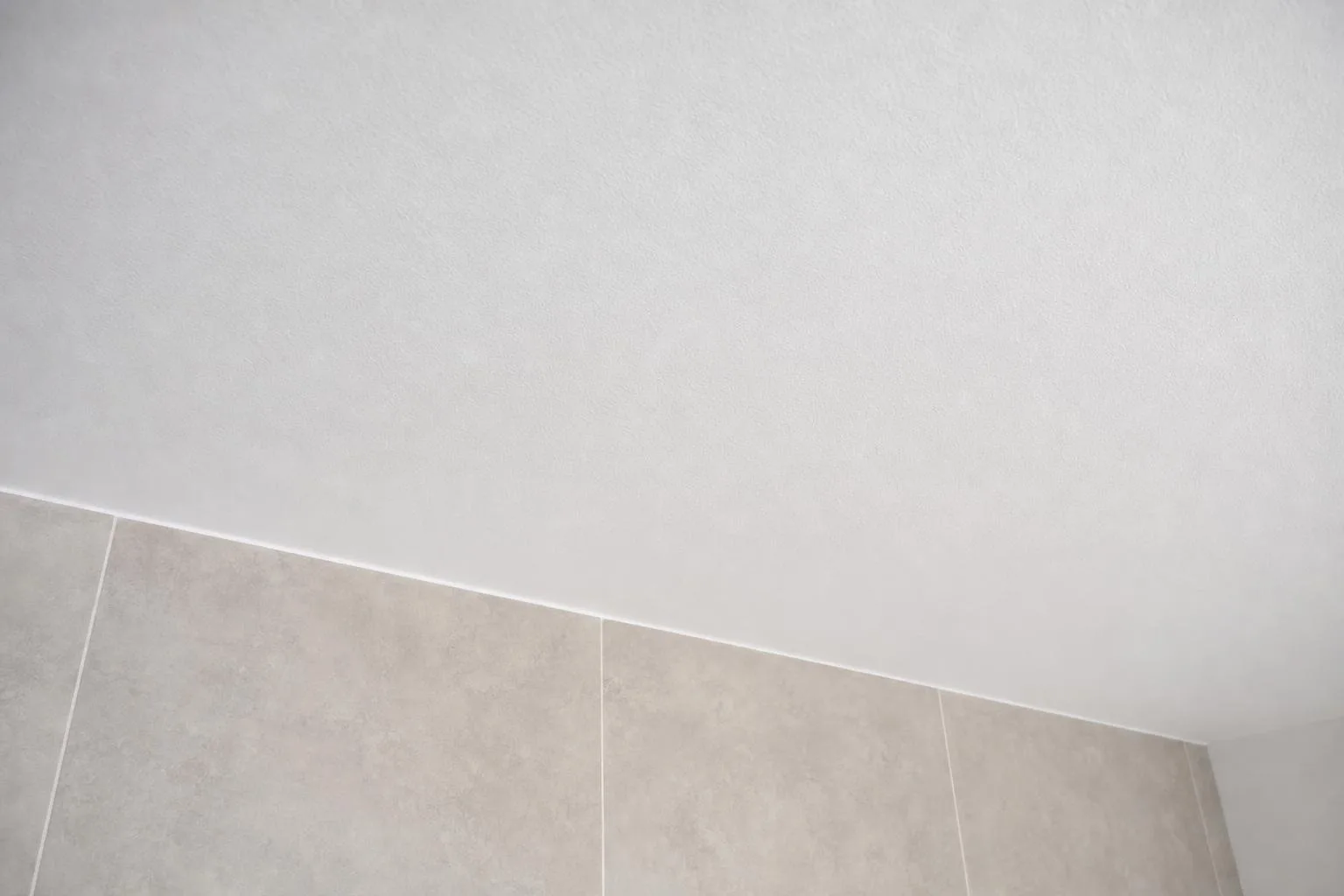 Detalle del techo de baño pintado sobre pared alicatada