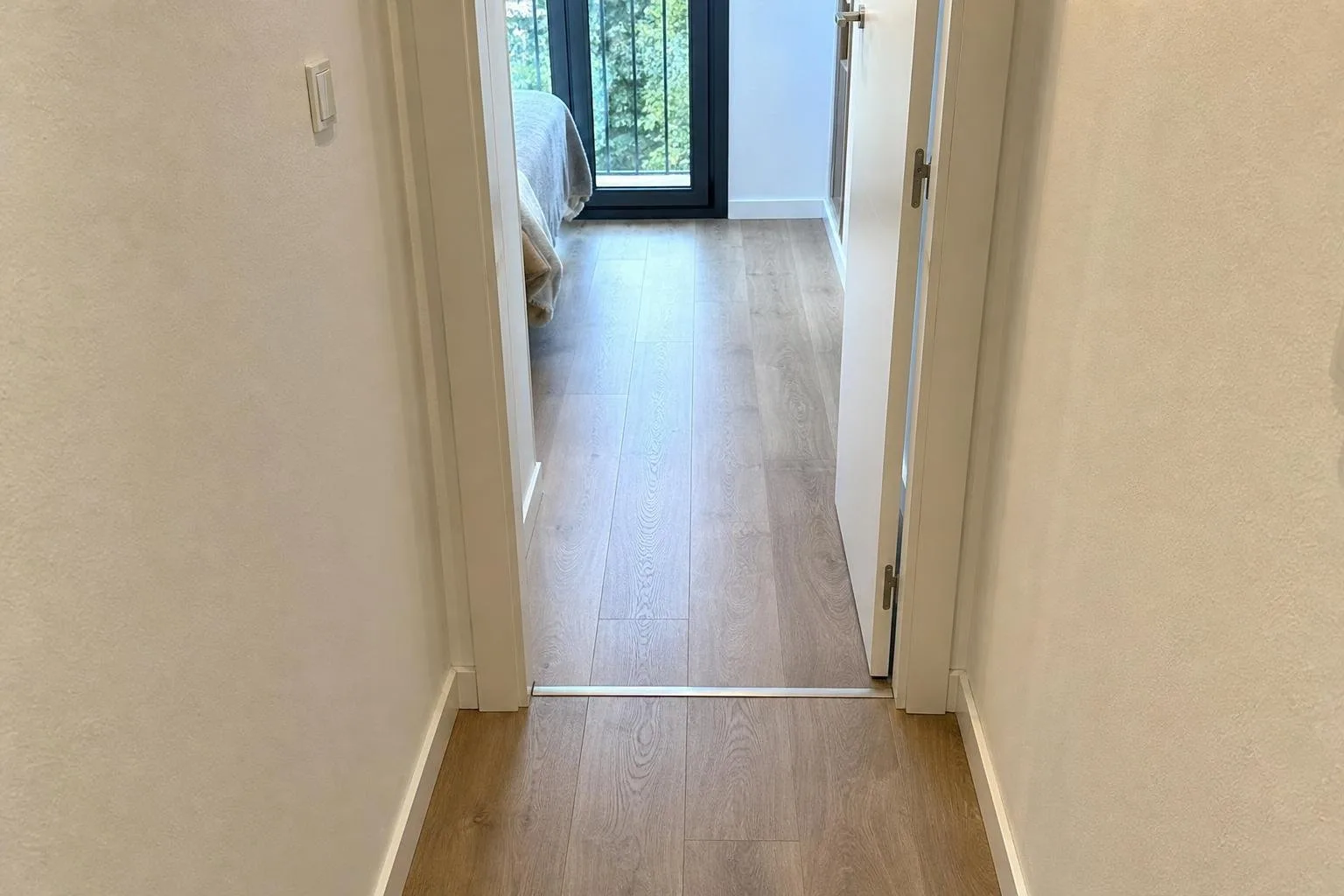 Pasillo con suelo laminado y perfil de transición en la puerta